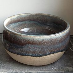 a large bowl sitting on top of a stone floor next to a white and black wall