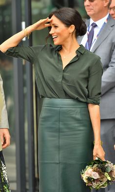 the woman is wearing a green dress and holding her hand on her head as she walks down the street