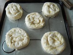 six uncooked doughnuts on a baking sheet