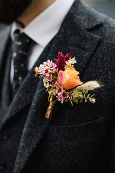 a man wearing a suit and tie with a boutonniere on his lapel