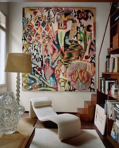 a living room filled with furniture and a large painting hanging on the wall above it