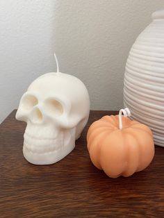 two white pumpkins sitting next to each other on top of a wooden table in front of a white vase