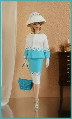 a barbie doll wearing a blue and white outfit with a handbag in front of a wall