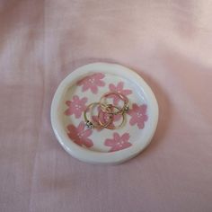 two wedding rings sitting on top of a pink and white plate covered in flower petals