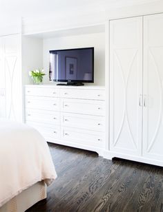 a bedroom with white furniture and a flat screen tv