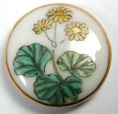 a white and green brooch with yellow flowers on it's back side,