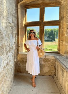 a woman standing in front of a window with her hands on her hips and wearing sunglasses