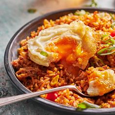 a close up of a plate of food with rice and meat on it, next to a fork