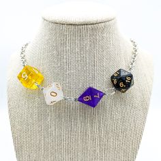 a necklace with three different colored dices on it's link, sitting on a mannequin