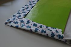 a piece of fabric is laying on top of a green mat with white and blue designs