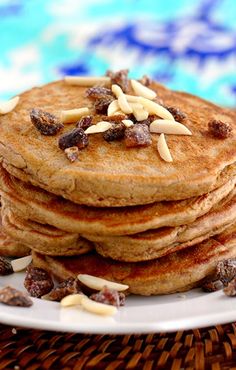 a stack of pancakes with nuts and raisins on top