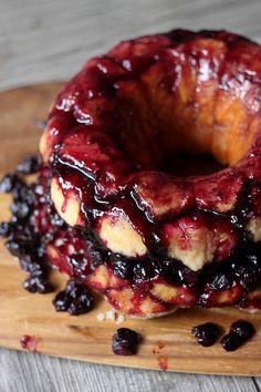 a bundt cake covered in blueberries on top of a wooden cutting board with raisins