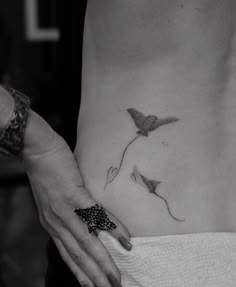 a black and white photo of a woman's stomach with two birds on it