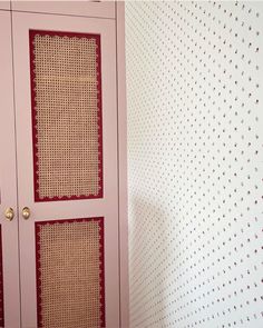 a pink cabinet sitting next to a wall with red and white designs on the walls