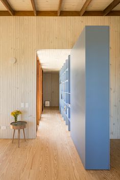 an empty room with wooden floors and blue shelves on the wall, next to a small table