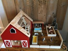 a toy farm with animals and people in the barn, on top of a wooden table