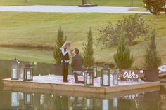 two people standing on a dock with lanterns