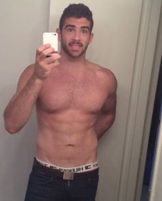 a shirtless man taking a selfie in the mirror