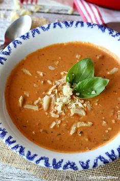 tomato basil parmesan soup in a white bowl on a blue and white plate