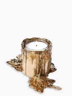 a candle that is sitting on top of a wooden stump with gold leaf decorations around it