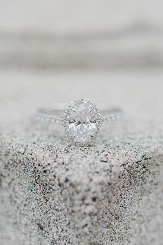 a diamond ring sitting on top of a stone block in the sand with gravel around it