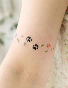 a small tattoo on the arm of a woman's left leg with paw prints