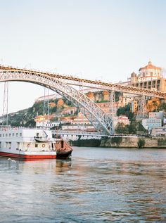 a large white boat floating on top of a river next to a bridge over water