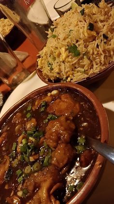 two bowls filled with food sitting on top of a table next to a plate of rice