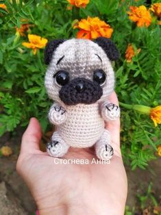 a small crocheted pug dog sitting on top of a person's hand