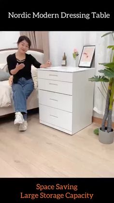 a woman sitting on top of a bed next to a white chest of drawers in a room