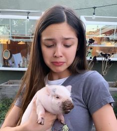 a woman holding a small pig in her hands