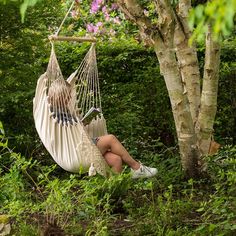 a woman sitting in a hammock between two trees