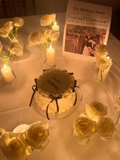 there is a cake on the table with candles and flowers in front of it,