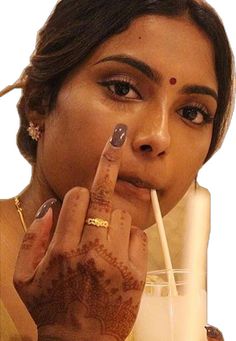 a woman with henna on her hand holding a straw in front of her face