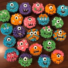 cupcakes decorated with different colored frosting and monster faces are arranged on a table