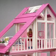 a doll house with a pink roof and balcony