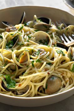 a bowl filled with pasta and clams on top of a table