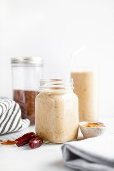 two jars filled with food sitting on top of a white counter next to other items