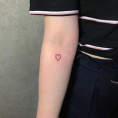 a small heart tattoo on the left arm