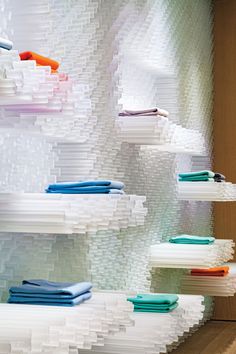 the shelves are stacked high with folded towels and napkins on them in different colors