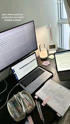 two laptops and a desktop computer sitting on a desk in front of a window