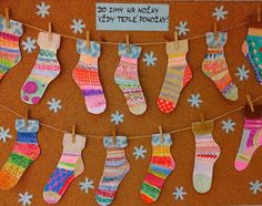 a bulletin board with colorful socks hanging from clothes pins and snowflakes on it