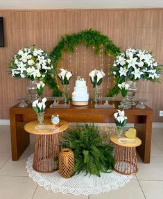 a table topped with lots of white flowers and greenery next to a cake on top of a wooden table