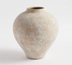 a white vase sitting on top of a table next to a white wall and floor