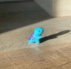 a blue toy dinosaur sitting on top of a wooden floor