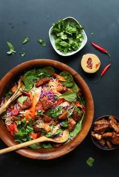 a wooden bowl filled with meat and veggies next to some dipping sauces