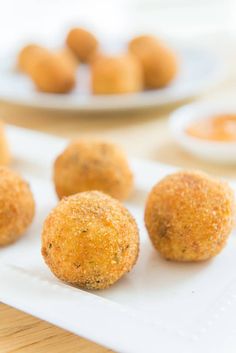 small balls of food sitting on a plate with dipping sauces in the bowl behind them