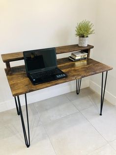 a laptop computer sitting on top of a wooden desk next to a plant and books