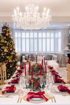 a dining room table set for christmas with red napkins and place settings on it