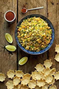 a bowl filled with corn and tortilla chips on top of a wooden table